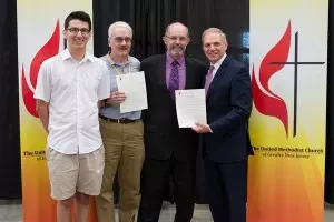Bishop John Schol (right) presents the appointment letter to pastor Jim.  Lay members Jeremy Andrade and Larry Bakely receive the church's copies of the letter.